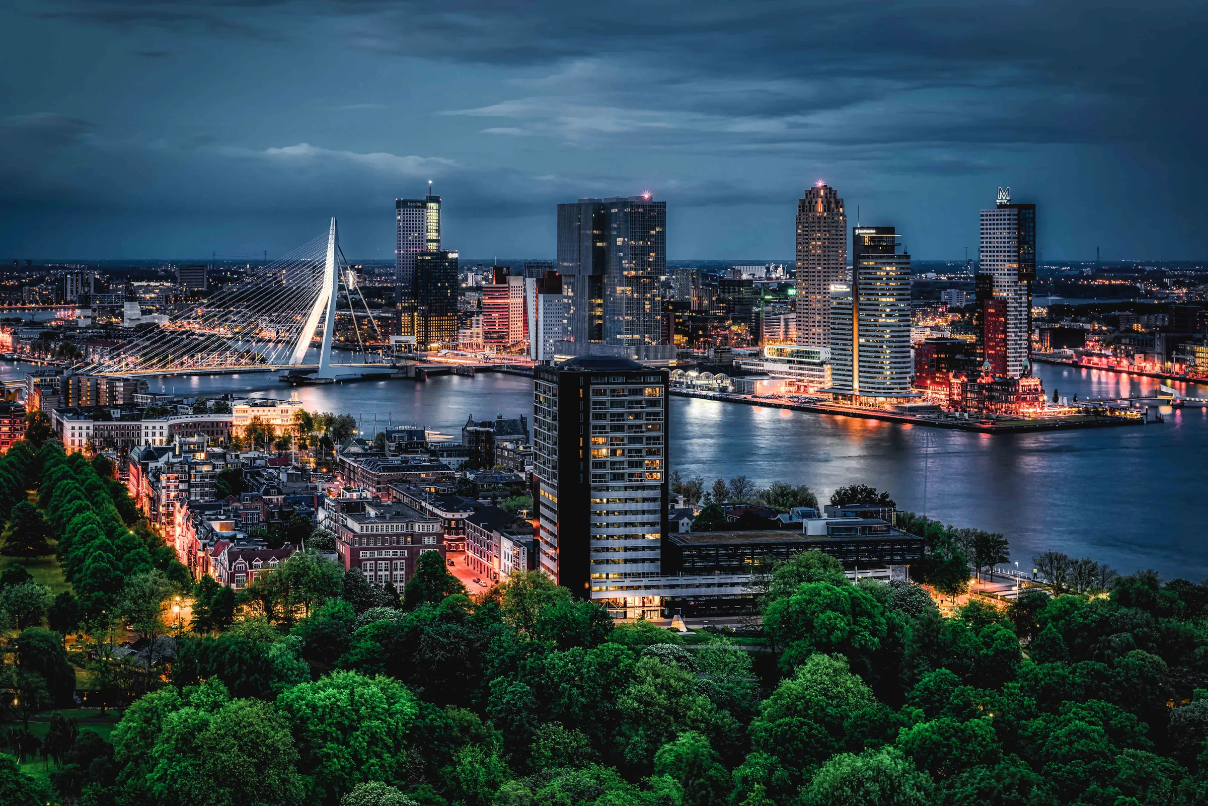 Brede opname van de skyline van Rotterdam bij schemering