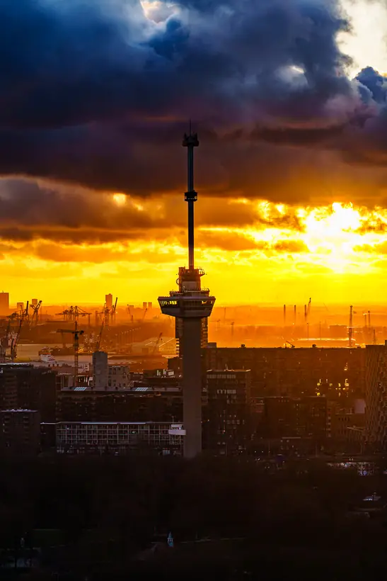 De Euromast tegen een dramatische oranje avondlucht