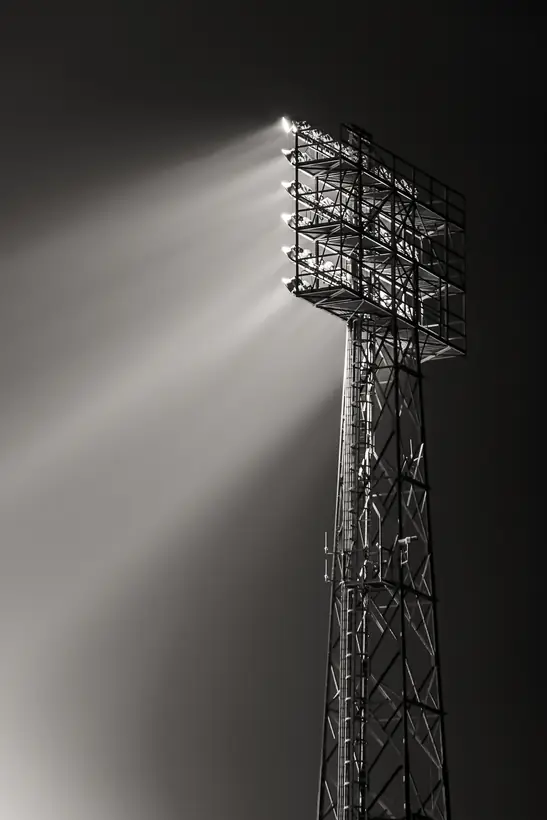 Zwartwit opname van een lichtmast met stralen door de mist