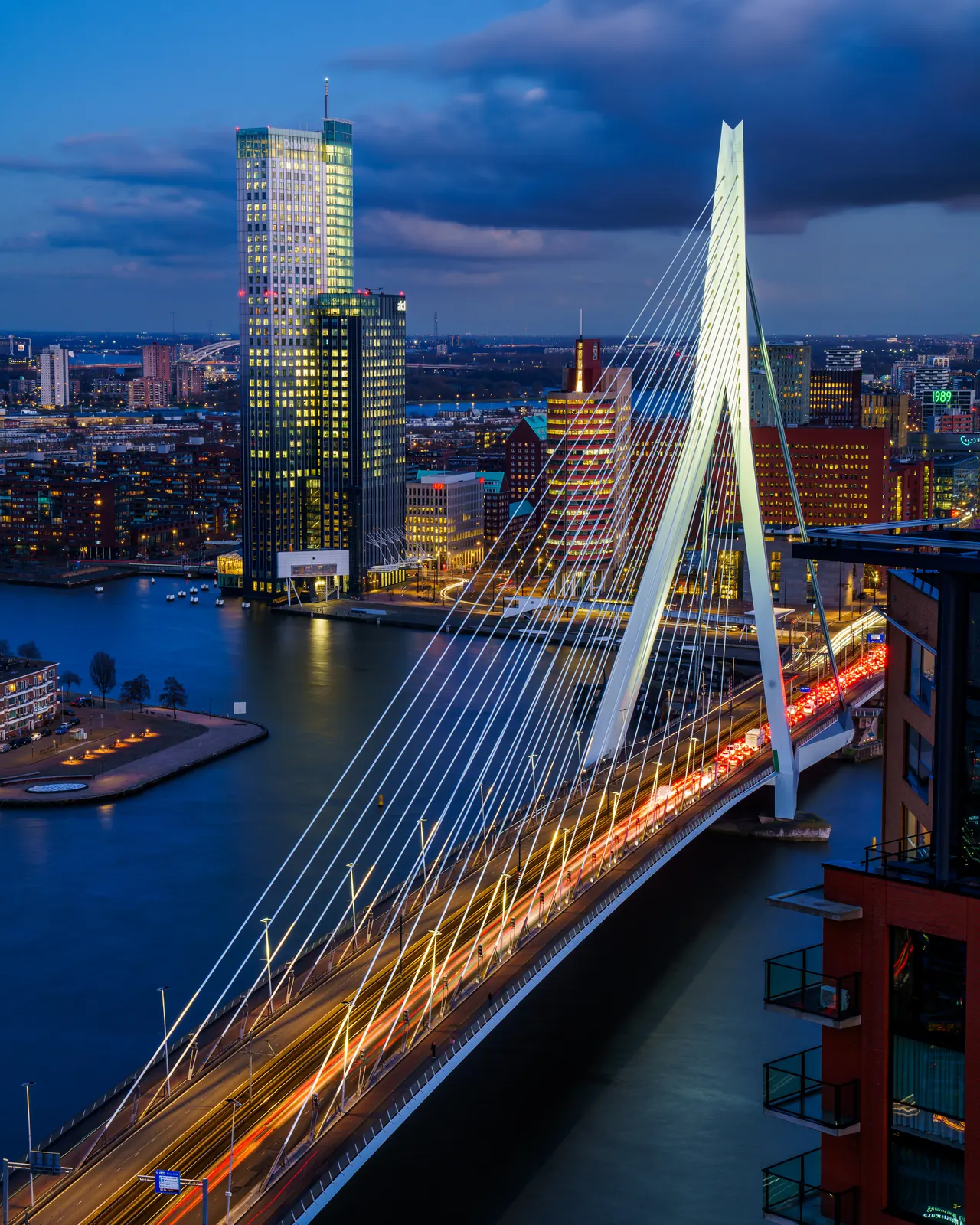 De Erasmusbrug vanaf een hoog standpunt, met lichtsporen en de stad op de achtergrond